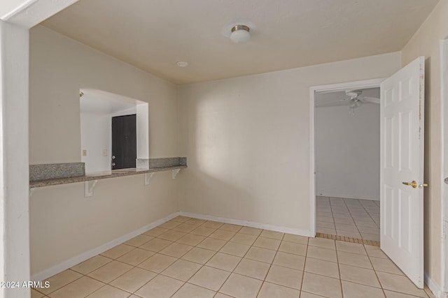 empty room featuring ceiling fan and light tile patterned floors