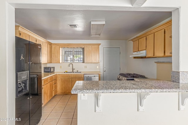 kitchen featuring kitchen peninsula, appliances with stainless steel finishes, a kitchen bar, and sink