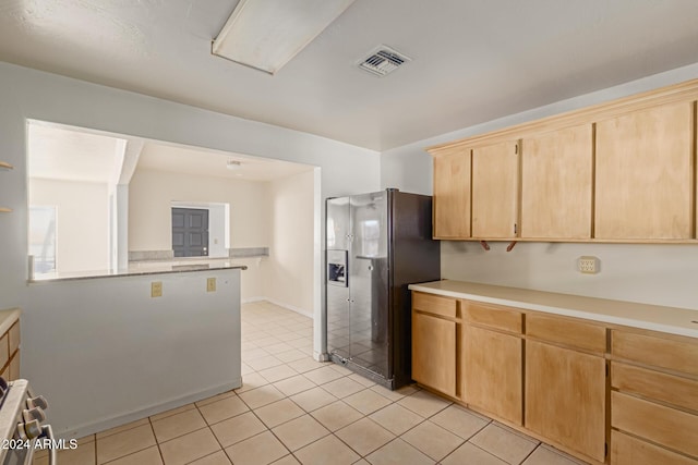 kitchen with stainless steel fridge, light brown cabinetry, and light tile patterned flooring