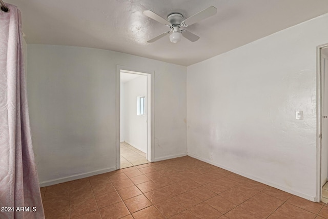 tiled spare room with ceiling fan