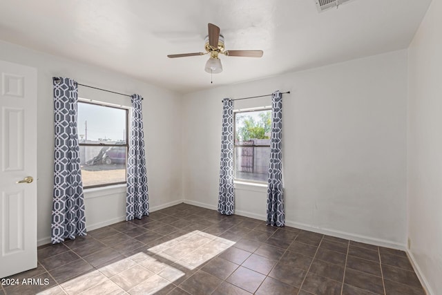 unfurnished room featuring dark tile patterned floors and ceiling fan