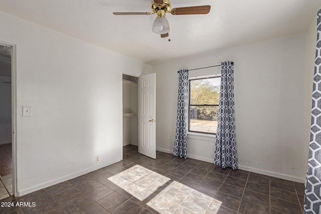 unfurnished bedroom featuring a closet, dark tile patterned floors, and ceiling fan