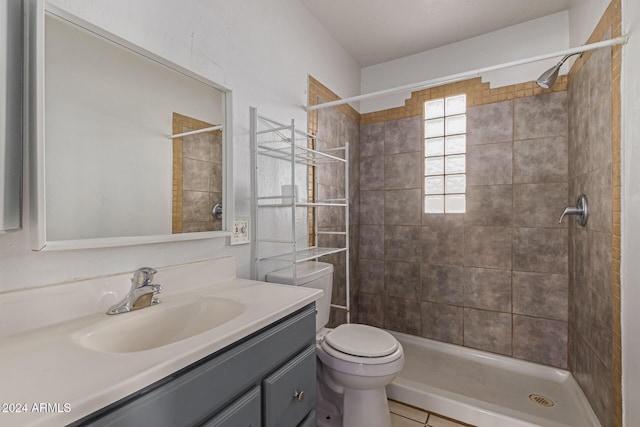 bathroom with tiled shower, vanity, tile patterned floors, and toilet