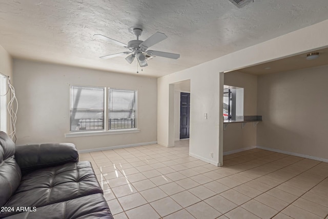 unfurnished living room with ceiling fan, light tile patterned flooring, and a textured ceiling