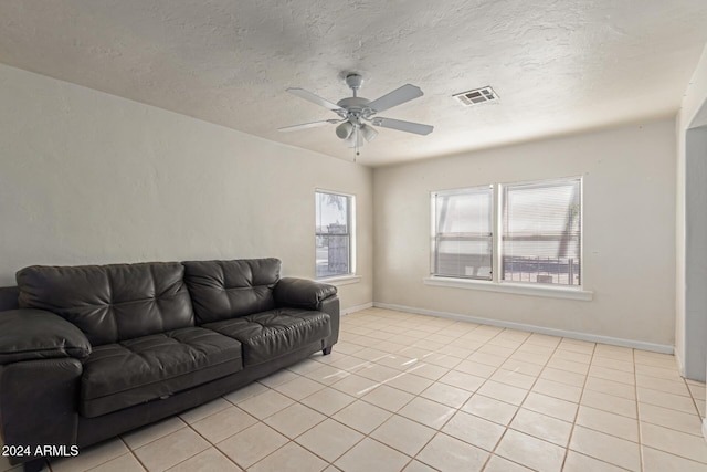 living room with ceiling fan, light tile patterned floors, and a textured ceiling