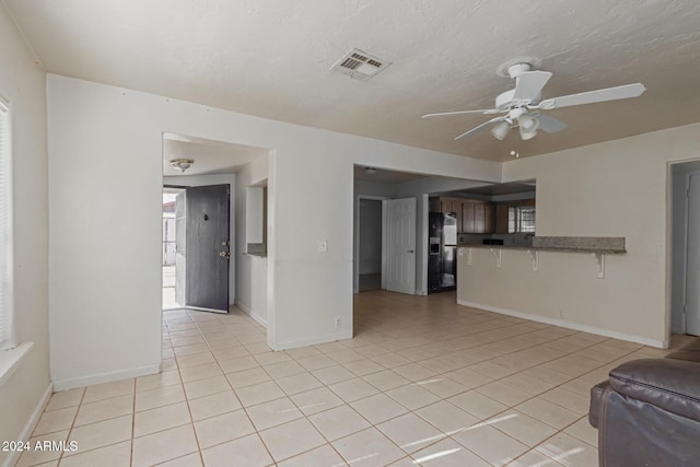 unfurnished living room with ceiling fan and light tile patterned floors