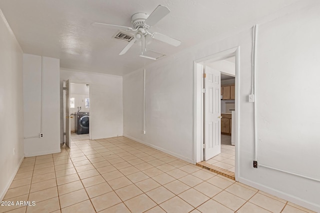 unfurnished room with washer / dryer, ceiling fan, and light tile patterned flooring