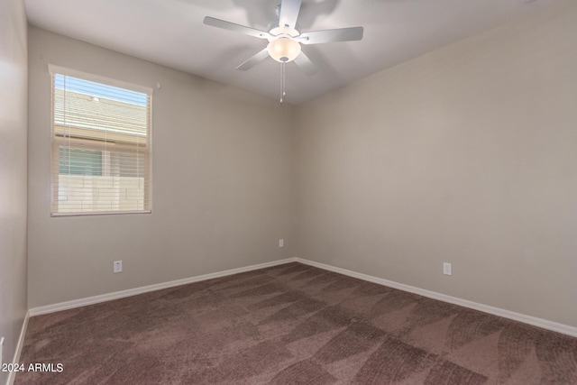 spare room featuring ceiling fan and dark carpet