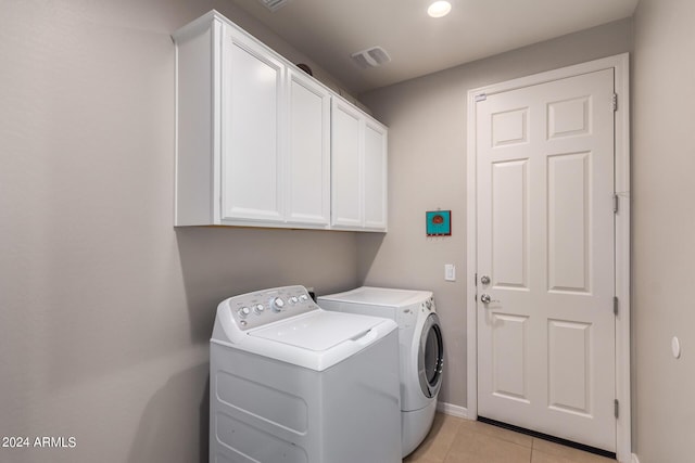 washroom with light tile patterned floors, independent washer and dryer, and cabinets