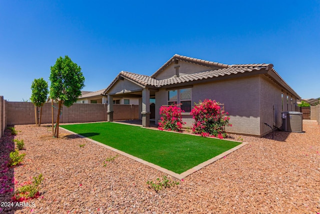 rear view of property featuring central AC and a lawn