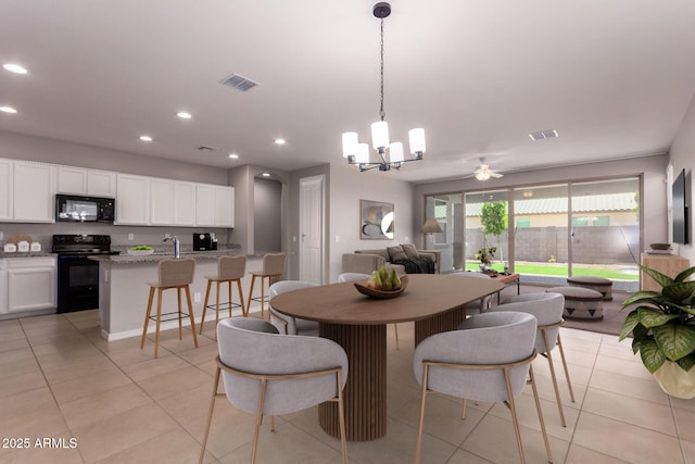 dining room featuring light tile patterned floors, sink, and ceiling fan with notable chandelier