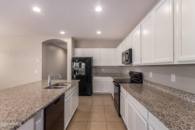 kitchen with black appliances, sink, light tile patterned flooring, light stone countertops, and white cabinets