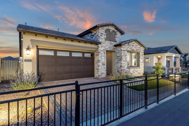 view of front of property featuring fence, driveway, stucco siding, a garage, and stone siding