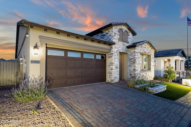 view of front of home with stone siding, a garage, driveway, and stucco siding