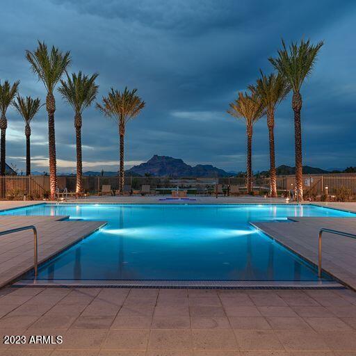 community pool with a patio area, fence, and a mountain view