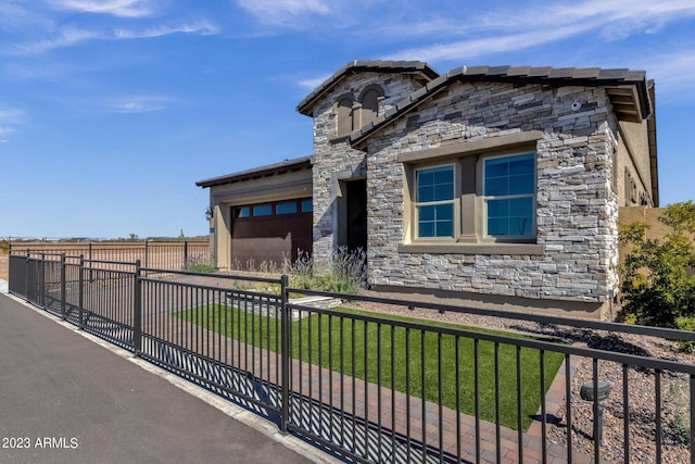 view of front of house featuring a fenced front yard, stone siding, a front lawn, and an attached garage