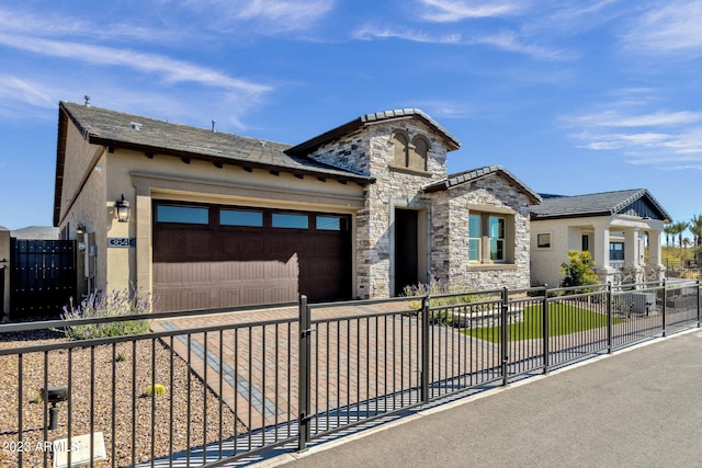 view of front facade with a fenced front yard, stucco siding, a garage, stone siding, and driveway