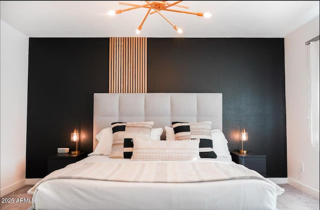 carpeted bedroom featuring baseboards, a chandelier, and an accent wall