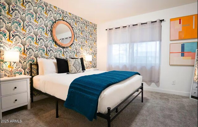 bedroom featuring carpet, baseboards, wallpapered walls, and an accent wall