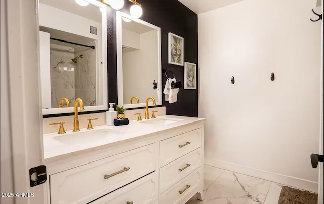 full bath featuring marble look tile flooring, a marble finish shower, baseboards, and double vanity