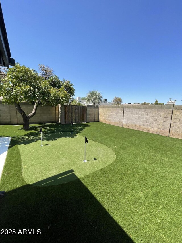 fenced backyard with a putting area