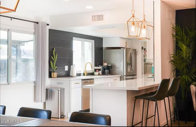 kitchen featuring stainless steel appliances, light countertops, white cabinetry, a breakfast bar area, and recessed lighting