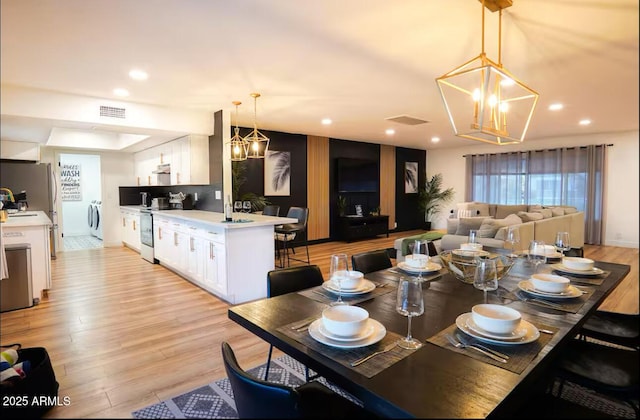 dining space with a chandelier, washer / clothes dryer, light wood finished floors, and recessed lighting