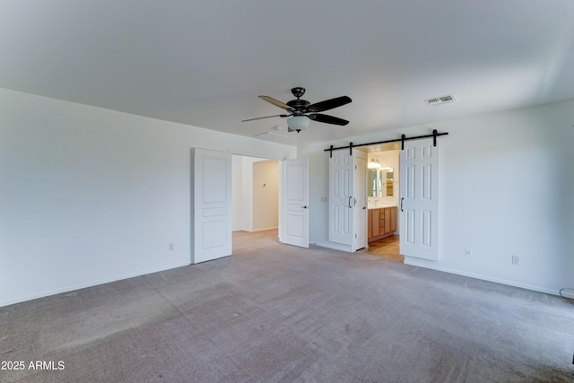 7398 W Paso Trl, Peoria, AZ 85383 - unfurnished bedroom featuring carpet, a barn door, connected bathroom, and a ceiling fan