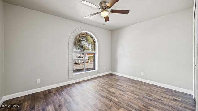 unfurnished room with baseboards, a ceiling fan, and dark wood-style flooring