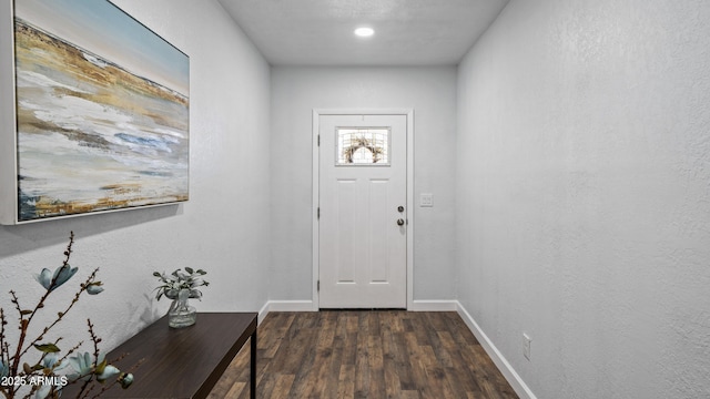 doorway to outside featuring dark wood-style floors, baseboards, and a textured wall