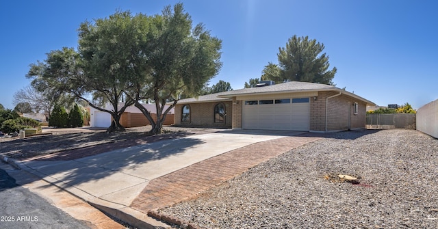 ranch-style home featuring concrete driveway, a garage, fence, and brick siding