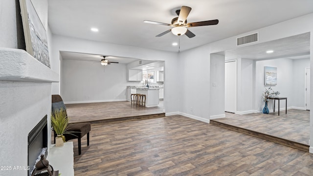 living room featuring visible vents, a fireplace, baseboards, and dark wood-style flooring