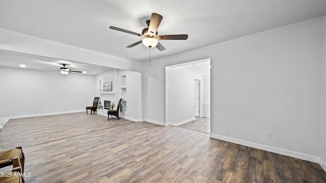 interior space with a glass covered fireplace, baseboards, and wood finished floors