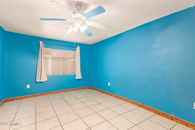 tiled empty room featuring ceiling fan