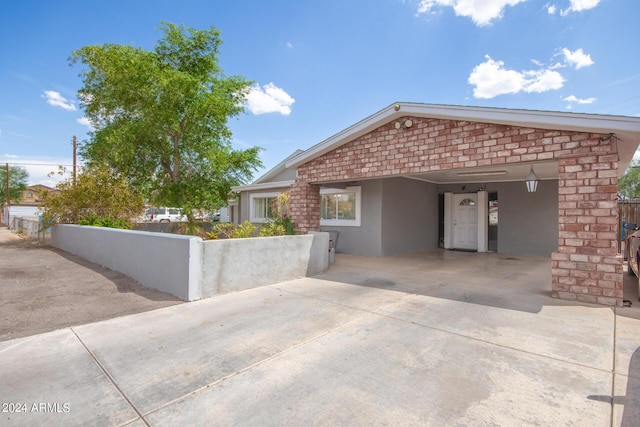 exterior space with fence, an attached carport, concrete driveway, and stucco siding