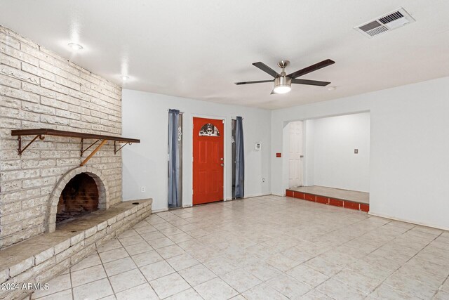 unfurnished living room with a brick fireplace, brick wall, ceiling fan, and light tile patterned flooring