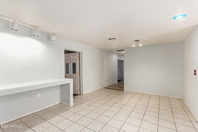 empty room with light tile patterned floors and track lighting