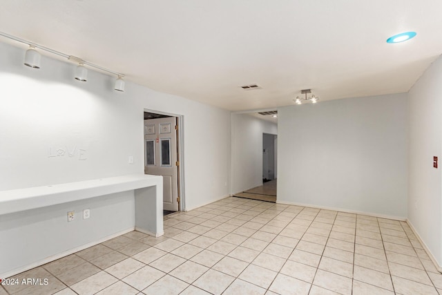 unfurnished room with track lighting, visible vents, baseboards, and light tile patterned floors