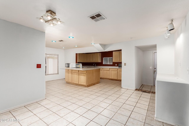 kitchen featuring light tile patterned floors, visible vents, white microwave, light countertops, and light brown cabinetry