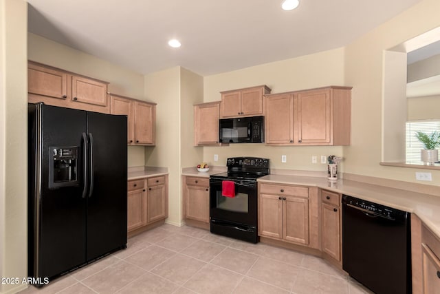 kitchen featuring light tile patterned flooring, light brown cabinets, and black appliances