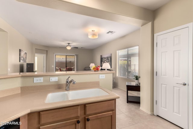 kitchen featuring ceiling fan, sink, and light tile patterned floors