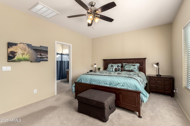 bedroom featuring connected bathroom, light colored carpet, and ceiling fan