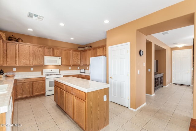 kitchen featuring light tile patterned floors, a kitchen island, and white appliances