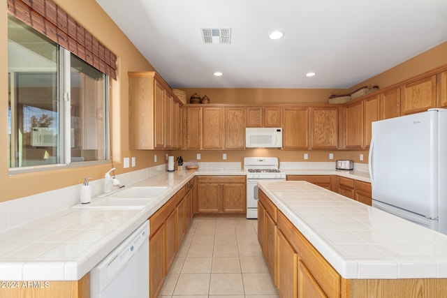 kitchen with white appliances, sink, light tile patterned flooring, a center island, and tile counters