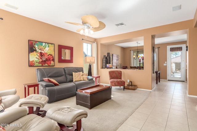 tiled living room with ceiling fan with notable chandelier