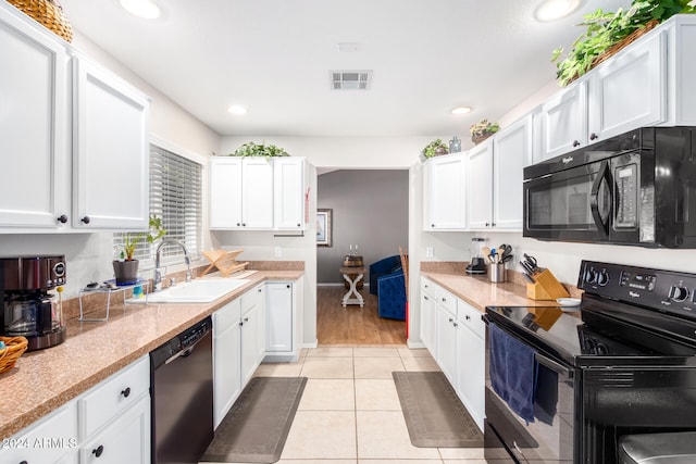 kitchen with light tile patterned floors, sink, white cabinetry, and black appliances