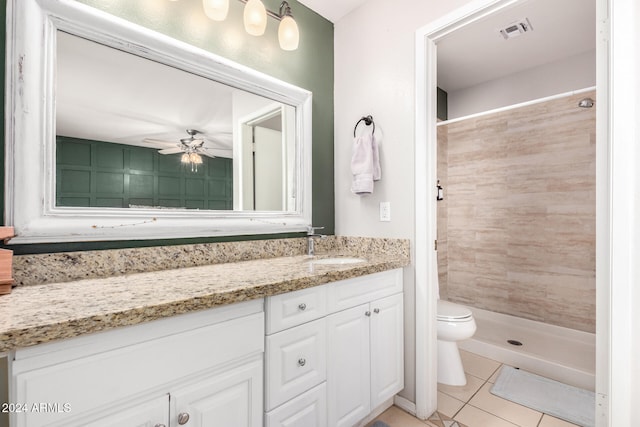 bathroom with ceiling fan, tile patterned flooring, tiled shower, toilet, and vanity