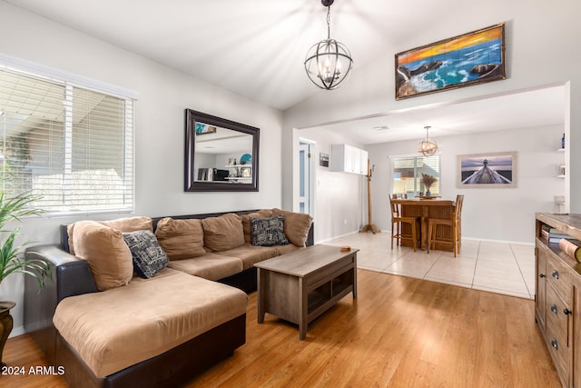 living room with lofted ceiling, light wood-type flooring, and an inviting chandelier