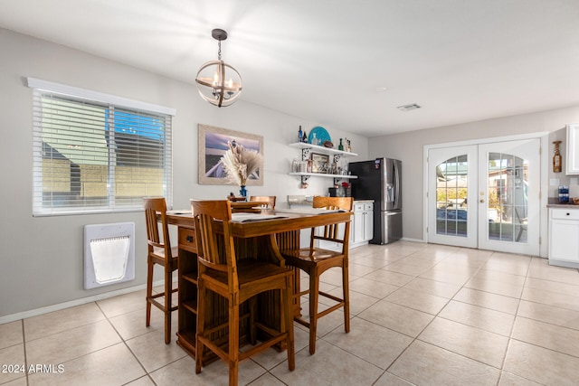 tiled dining room featuring heating unit, french doors, and a notable chandelier