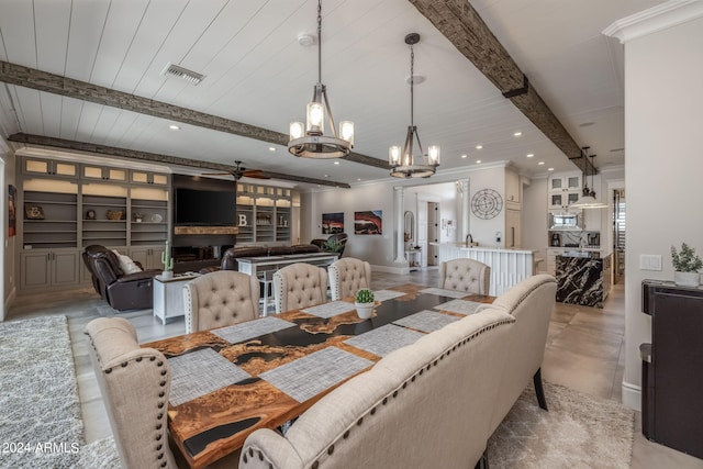 dining room featuring ceiling fan with notable chandelier, crown molding, built in features, and a fireplace